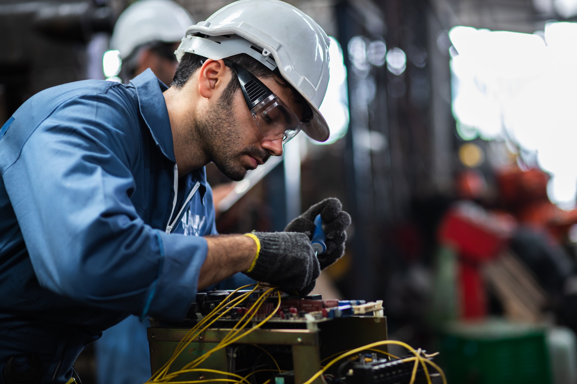 Engineer manual workers standing in a aluminum mill and working together. used professional equipment. Manual workers cooperating while measuring a electronic.