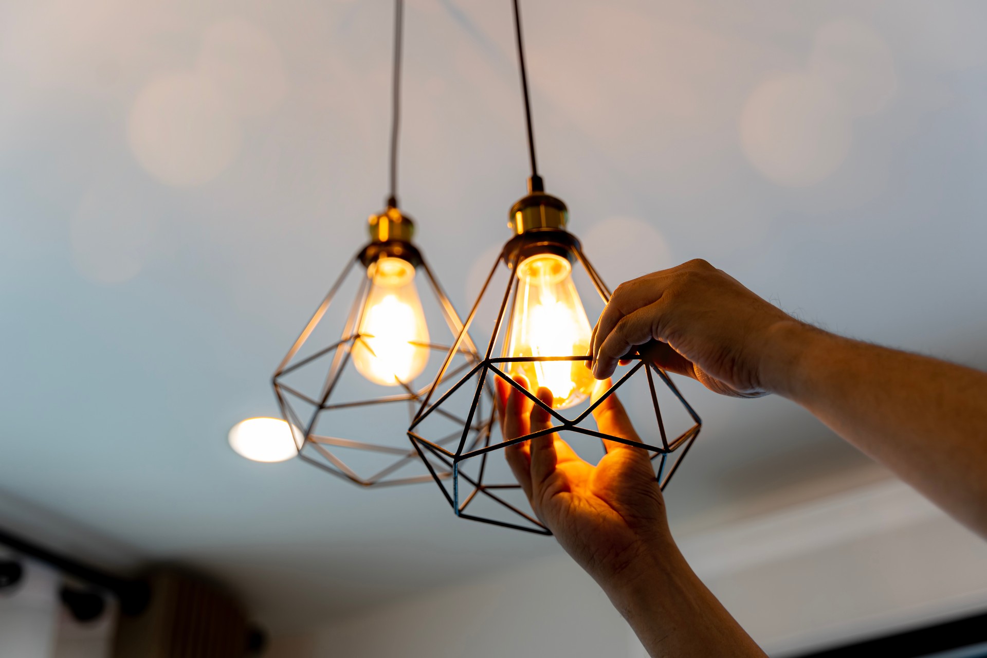 Decorative antique edison style filament light bulbs hanging. An electrician is installing spotlights on the ceiling